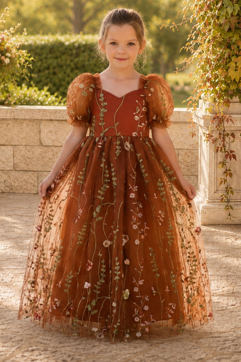 flower girl dress in burnt orange floral embroidered tulle. Featuring a sweat heart neckline, puffy short sleeves and a full length dress.