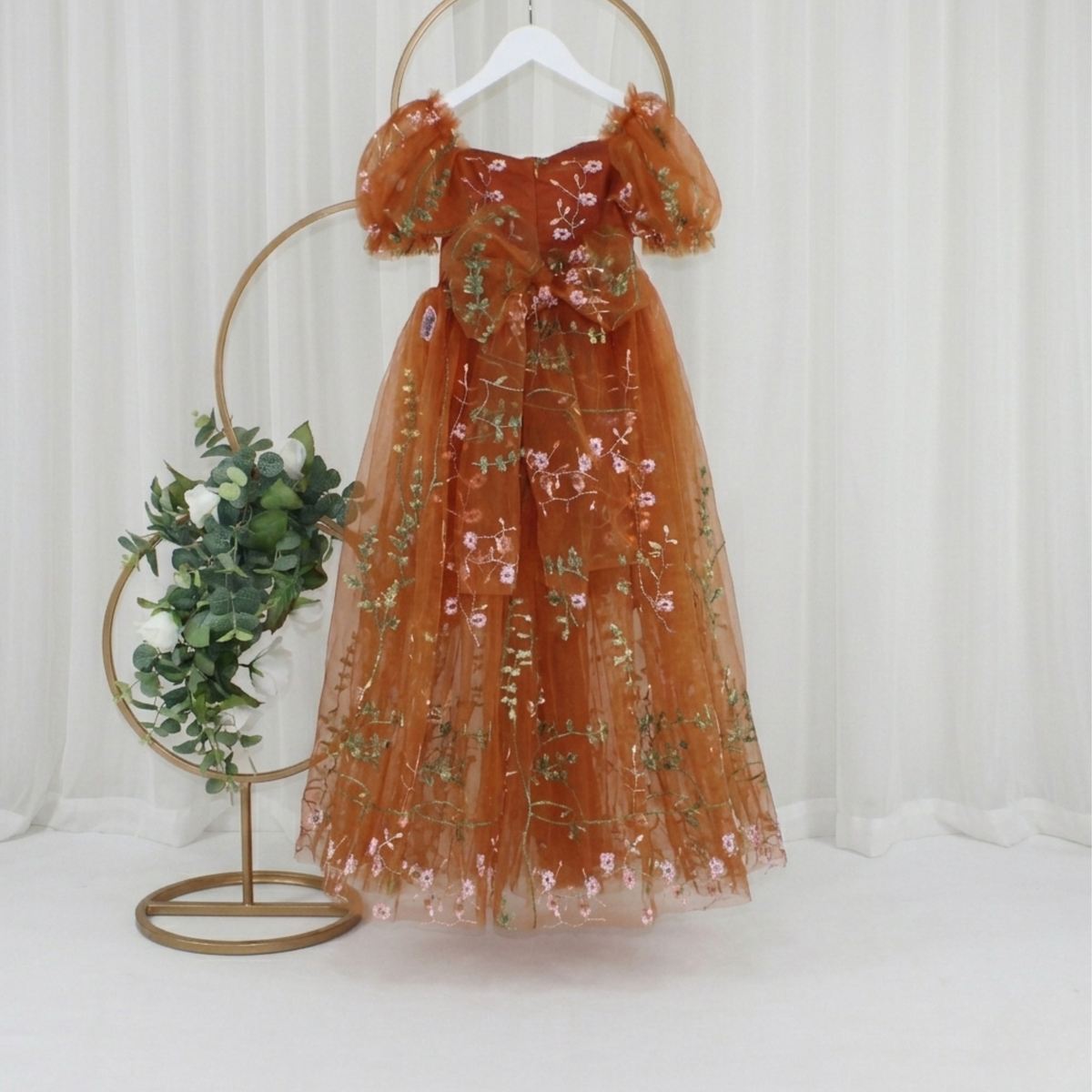 back of the dress flower girl dress in burnt orange floral embroidered tulle. Featuring a sweat heart neckline, puffy short sleeves and a full length dress.