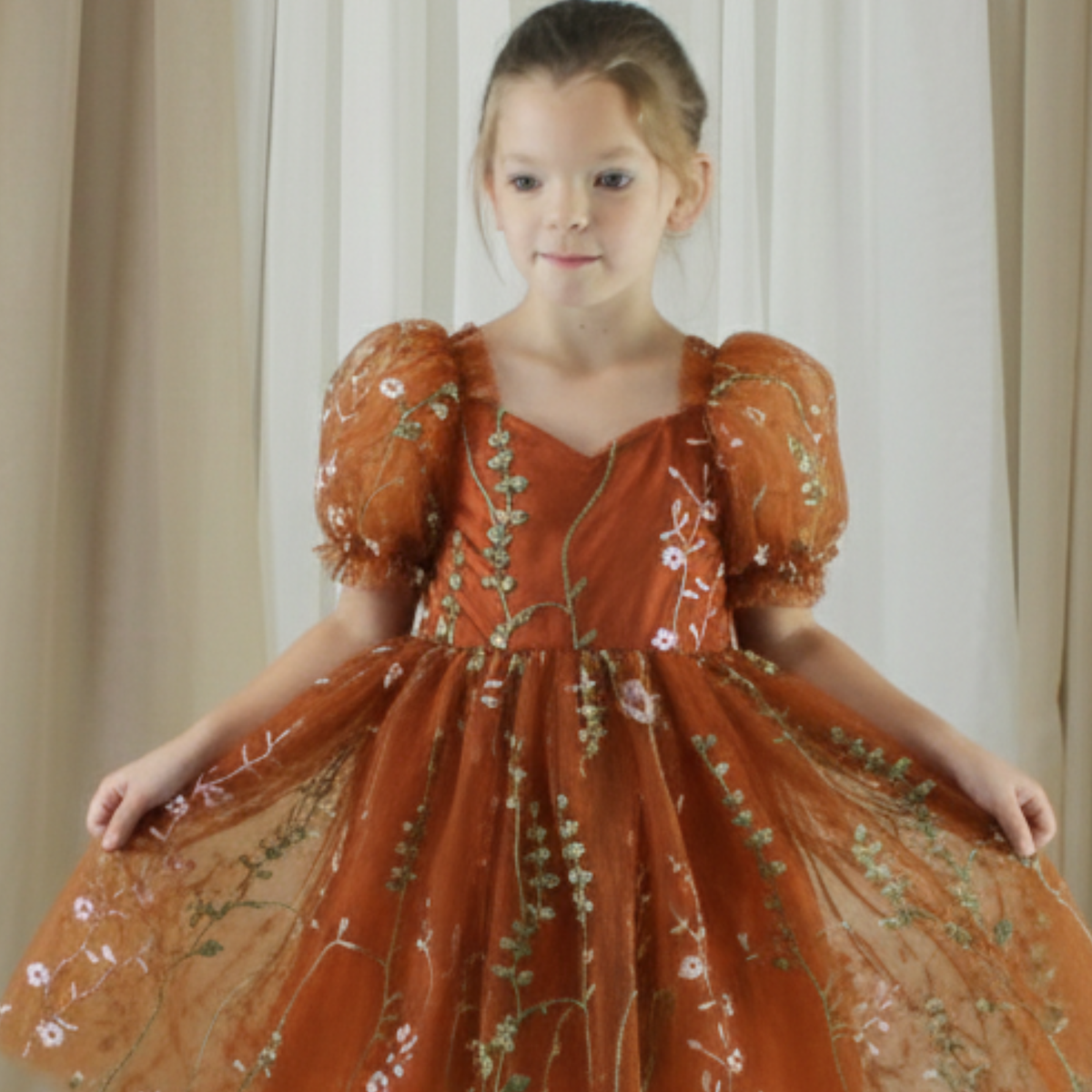 fall flower girl dress in burnt orange floral embroidered tulle. Featuring a sweat heart neckline, puffy short sleeves and a full length dress.
