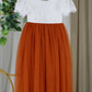 Orange flower girl dress shown from the back with white lace and satin sash