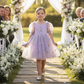 flower girl dress in lavender floral embroidery with big puffy sleeves and big sash bow in back. 