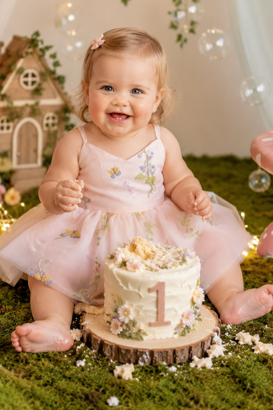 first birthday dress baby girl in embroidered light pink floral in a romper bodysuit style.  