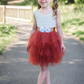 Flower girl dress in rust tulle tiered tutu style with white lace sleeveless top. 