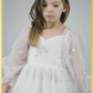 Close up of flower girl dress. White tulle with tulip print. Dress is long tulle sleeves and made to hit at the knee. 